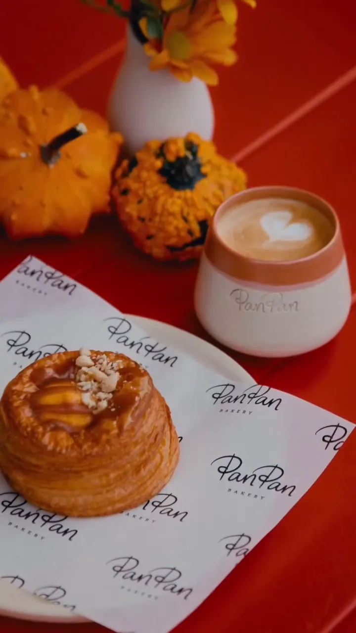 A milk coffee and a fresh pastry on a table